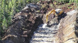 A backhoe clears MetalCorp's Pickle Lake property for subsequent trenching.