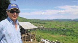 Moto Goldmines project manager Greg Smith stands above a valley surrounding the company's prospective gold property in northeastern Congo. Behind him is a Belgian-built mill near the Durba gold mine, which still operates when there is sufficient feed.