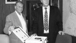 HY-DRIVE TECHNOLOGIESHy-Drive CEO Tom Brown (left) and MTI CEO Bob Lipic sign an agreement whereby mining equipment builder MTI will use Hy-Drive's patented HGS technology in certain diesel and gas-burning vehicles. The Hy-Drive prototype is shown.