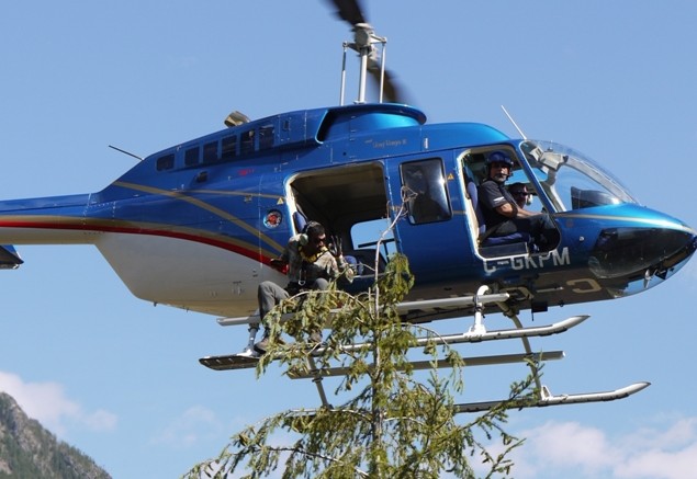 Student environmentalist Haj Bains signals to helicopter pilot Michael King after collecting a treetop sample in west-central British Columbia. Photo credit: Bruce Madu